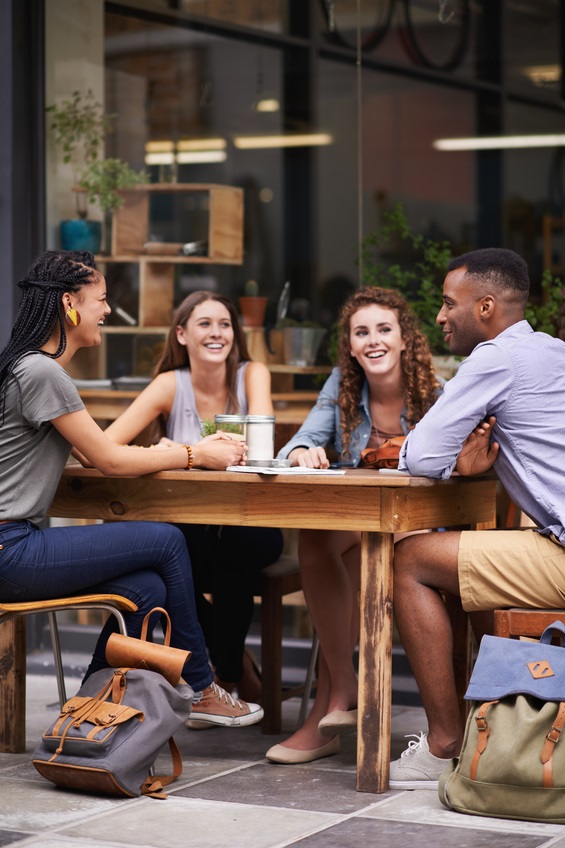 A group of young friends sitting outside at a sidewalk cafe