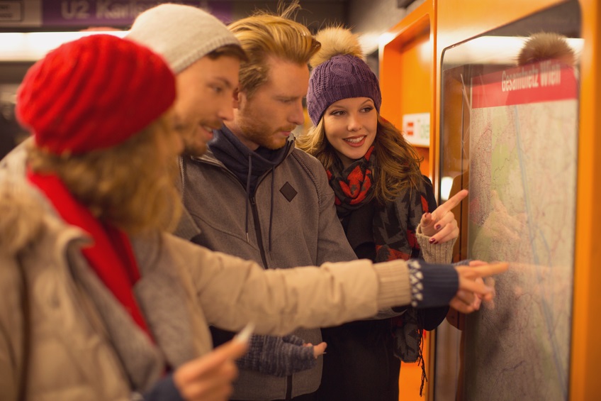 Friends at subway station studying the map. Wearing warm clothes, hats and scarfs. Vienna, Austria.