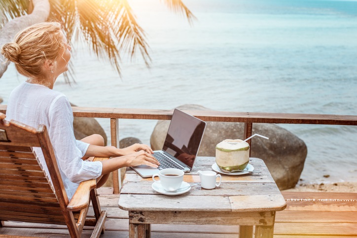 Young woman working on laptop with coffee and young coconut